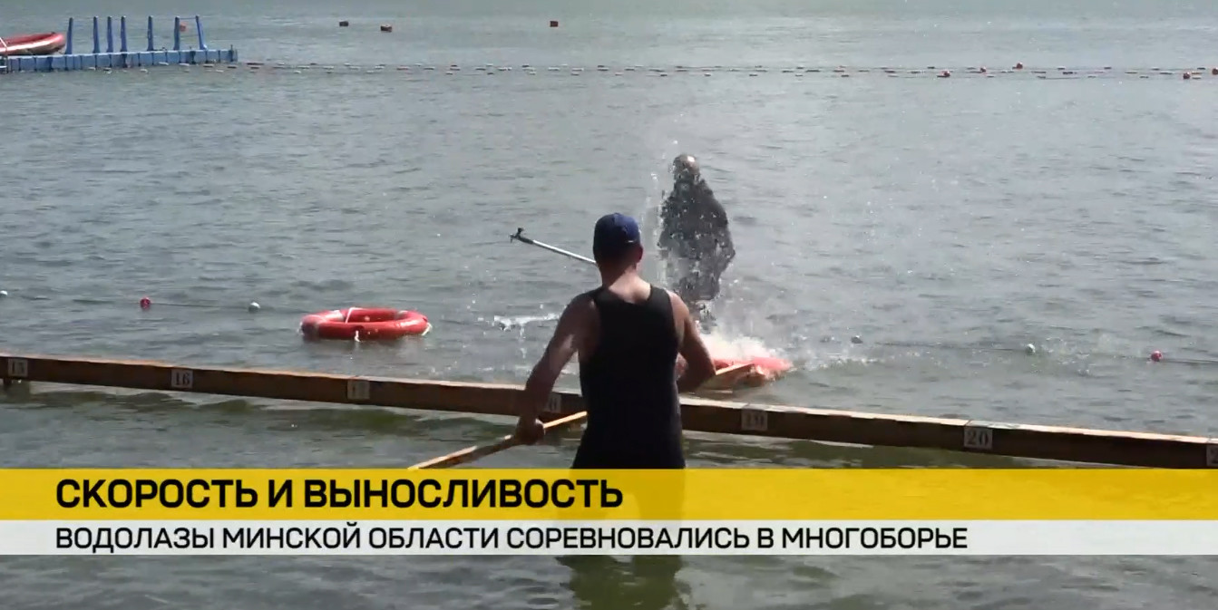 Мужчина со спины в майке и кепке стоит в воде с веслом у деревянного пирса. Впереди водолаз выходит из воды. На воде спасательный круг. Внизу желтая новостная плашка ОНТ.